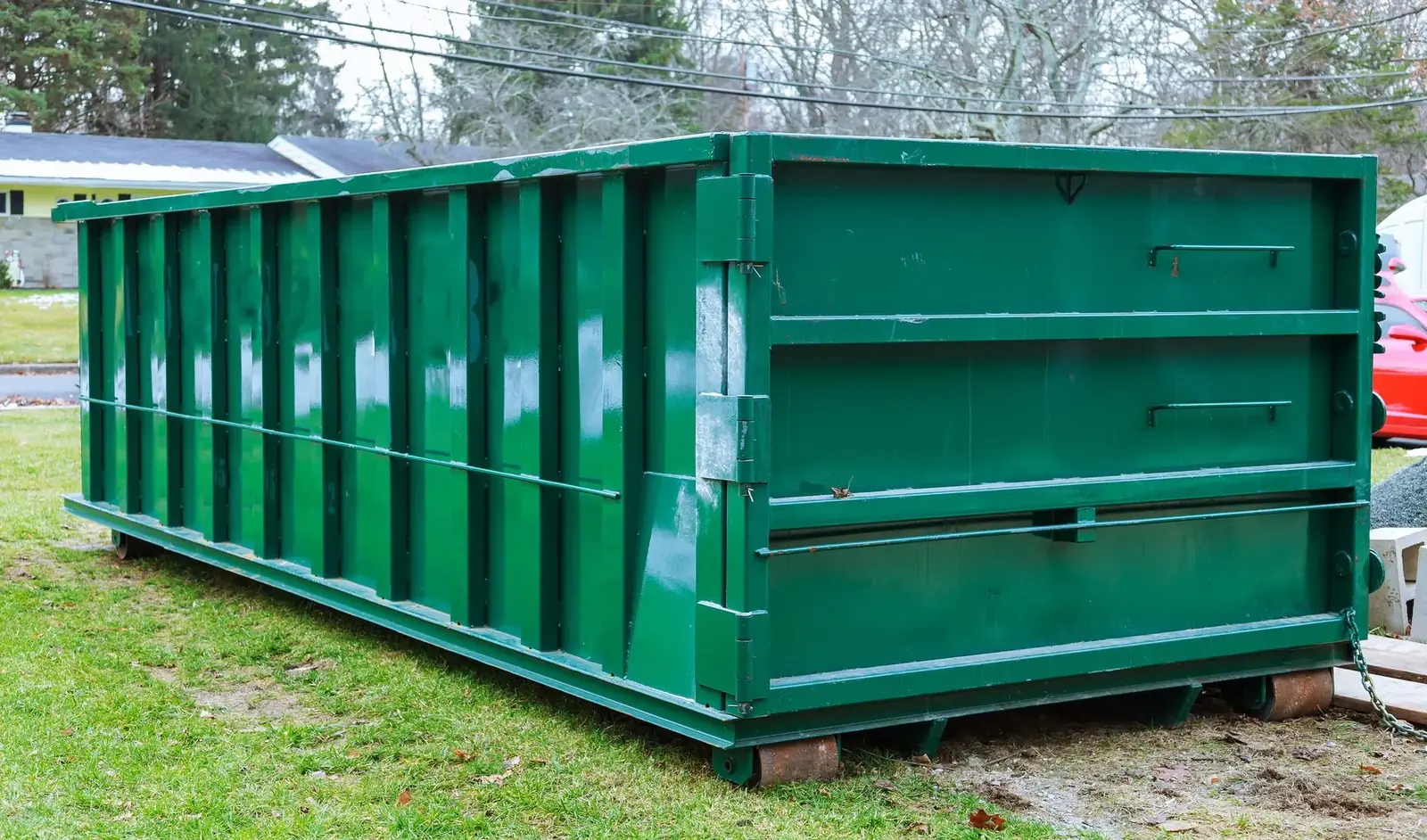 Green roll-off dumpster set on wood boards on a lawn